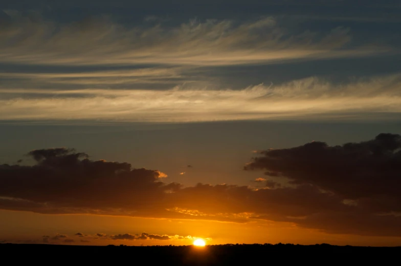 the sun is setting behind the clouds in the sky, by Peter Churcher, unsplash, romanticism, shot on 1 5 0 mm, brown, shot on sony a 7, horizon