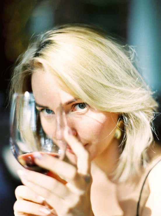 a woman holding a wine glass in front of her face, a portrait, pexels contest winner, photorealism, blonde swedish woman, avatar image, low quality grainy, headshot profile picture