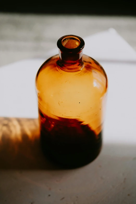 a bottle sitting on top of a table next to a cork, by Rebecca Horn, unsplash, visual art, sunny amber morning light, made of glazed, 1850s, detail shot