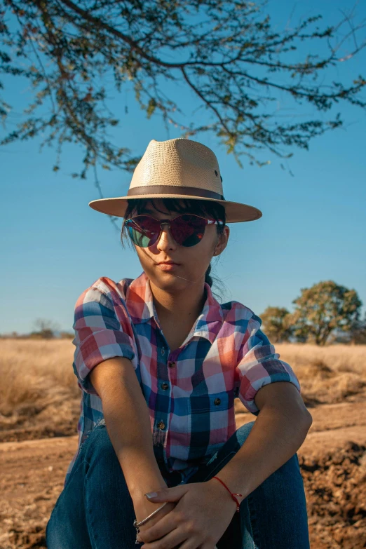 a woman sitting under a tree wearing a hat and sunglasses, rugged ranger, darren quach, androgynous person, outback