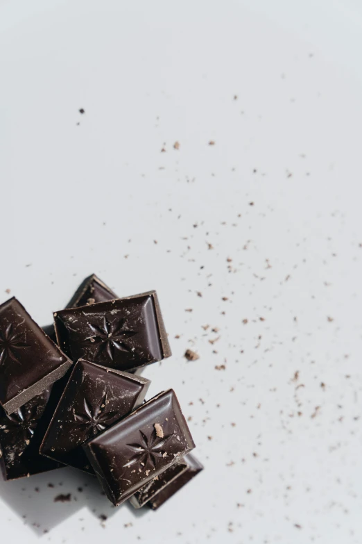 a white plate topped with pieces of chocolate, trending on pexels, hemp, space dust, black, 1 6 x 1 6