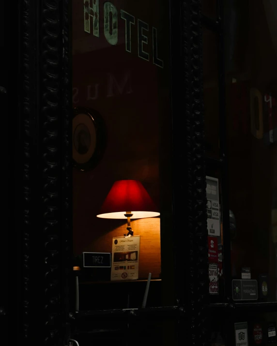 a lamp sitting on top of a table next to a window, inspired by Brassaï, unsplash contest winner, miniature cafe diorama, red cap, ignant, night photo