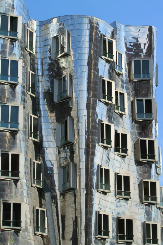 a very tall building with lots of windows, inspired by Gaudi, cubism, shiny silver, “derelict architecture buildings, frank gehry, curving