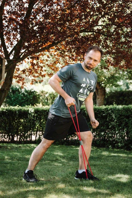 a man that is standing in the grass with a frisbee, carrying two barbells, jakub rebelka, pulling strings, at home