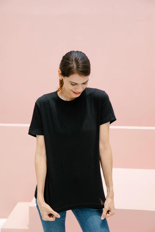 a woman standing in front of a pink wall, inspired by Eva Gonzalès, minimalism, wearing black tshirt, organic dress, main colour - black, tunic