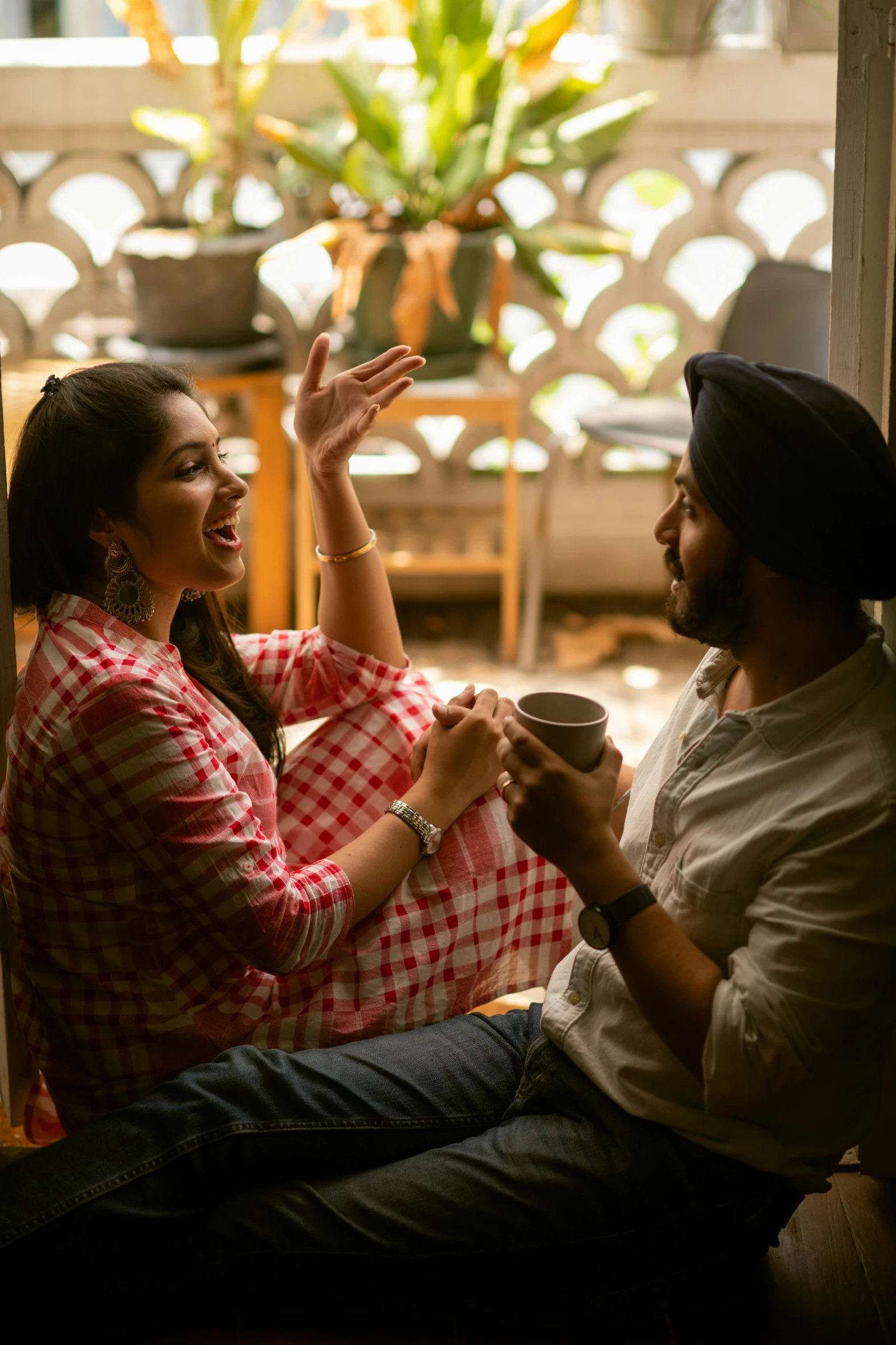 a man and a woman sitting on a window sill, by Manjit Bawa, pexels contest winner, smiling at each other, drinking, waving, indoor scene