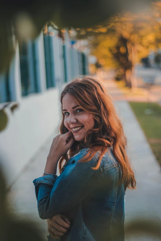 a woman standing on a sidewalk talking on a cell phone, a picture, pexels contest winner, attractive brown hair woman, smiling :: attractive, headshot profile picture, goldenhour