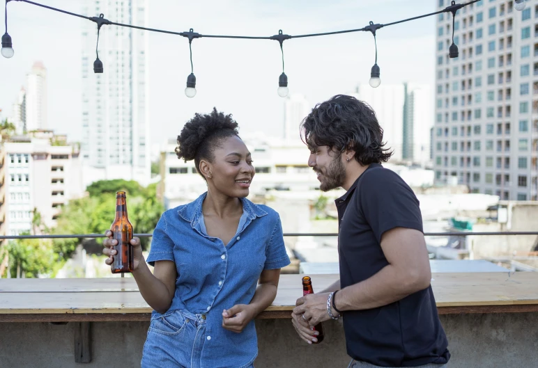 a man and a woman standing next to each other, pexels contest winner, rooftop party, holding beer bottles, profile image, hispanic