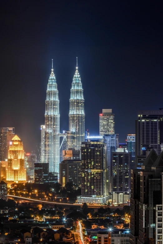 an aerial view of a city at night, inspired by Evgeny Lushpin, pexels contest winner, hurufiyya, malaysian, tall spires, back, three towers