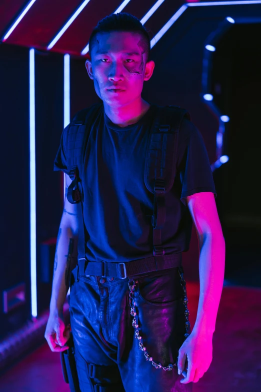 a man standing in front of a neon tunnel, an album cover, trending on pexels, bauhaus, holding arms on holsters, nonbinary model, runway photo, dark. studio lighting