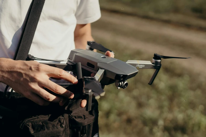 a close up of a person holding a small drone, pexels contest winner, plein air, iridescent technology and weapon, rectangle, farming, looking to the side off camera