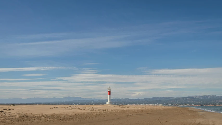 a red and white lighthouse sitting on top of a sandy beach, a picture, by Eglon van der Neer, marbella landscape, wide open city ”, albuquerque, midday photograph