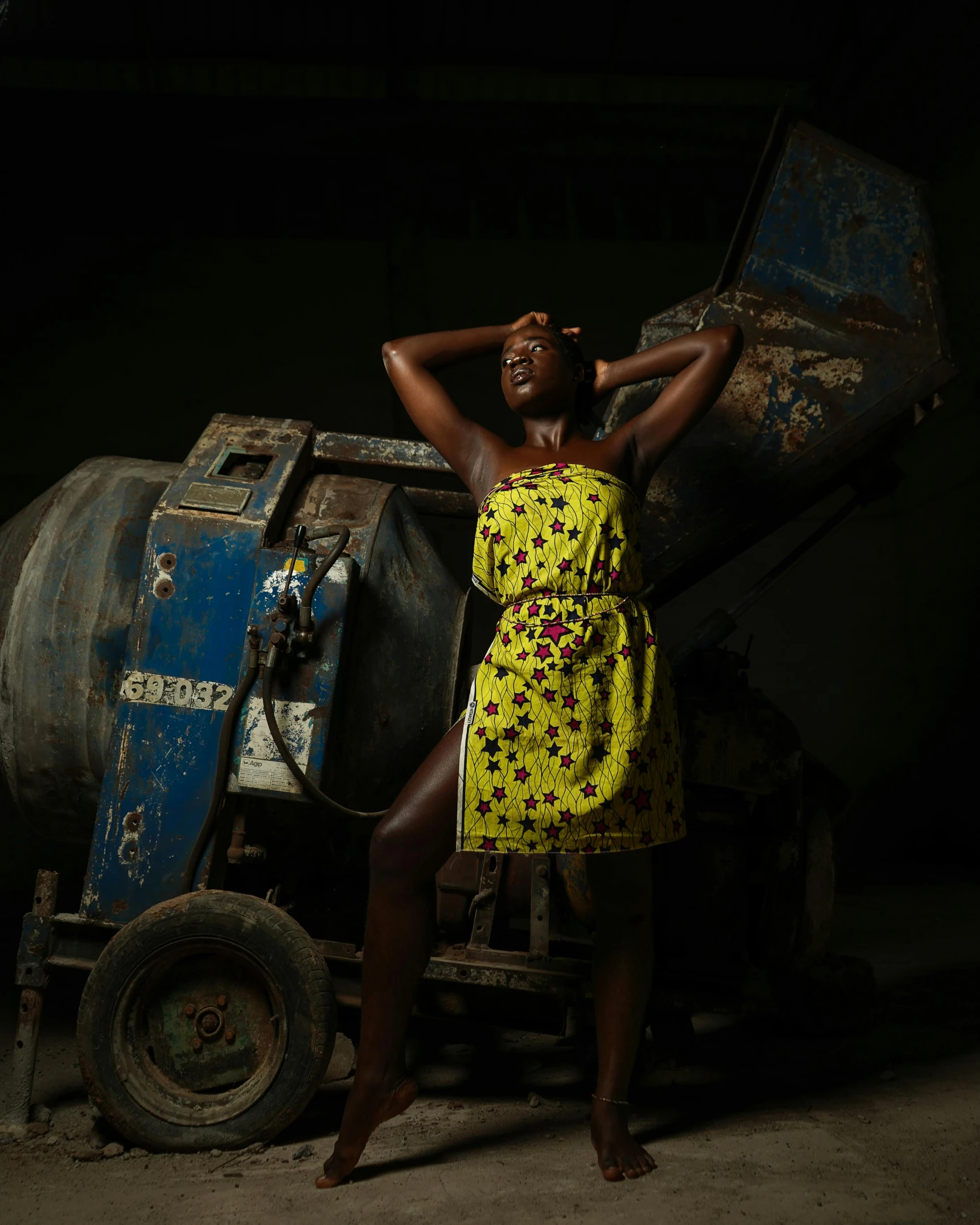 a woman in a yellow dress standing next to a cement mixer, pexels contest winner, afrofuturism, dark skin, fashion studio lighting, taken in the late 2010s, dress made with circuit board