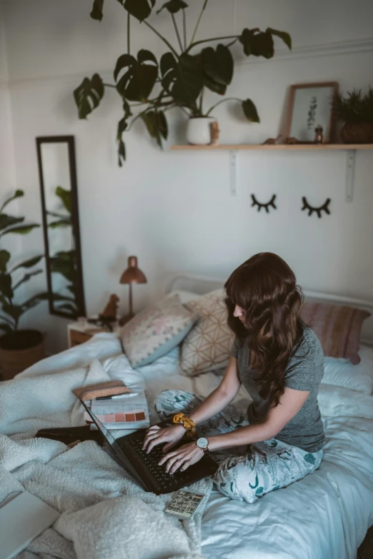 a woman sitting on a bed using a laptop, pexels contest winner, happening, girl with brown hair, covered in plants, low quality photo, music being played