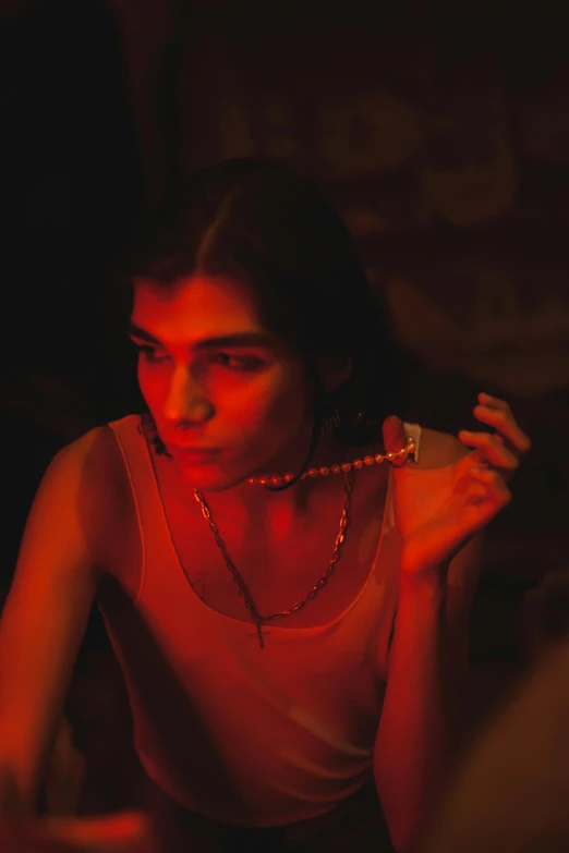 a woman sitting at a table with a cigarette in her hand, an album cover, inspired by Nan Goldin, trending on pexels, red jewelry, dua lipa, ( ( theatrical ) ), grainy movie still