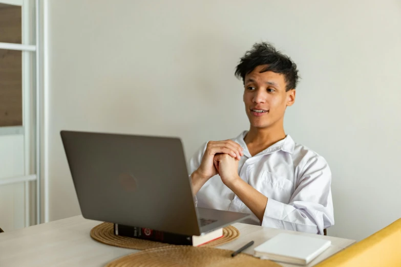 a man sitting at a table with a laptop, non-binary, looking cute, peruvian looking, professional image