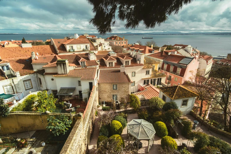 a view of a city from the top of a building, inspired by Almada Negreiros, pexels contest winner, medieval coastal village, backyard, tiled roofs, brown