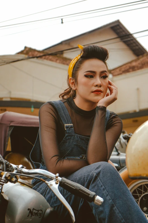 a woman sitting on a motorcycle talking on a cell phone, inspired by Rudy Siswanto, trending on pexels, photorealism, looking serious, girl with messy bun hairstyle, vintage clothing, black and yellow