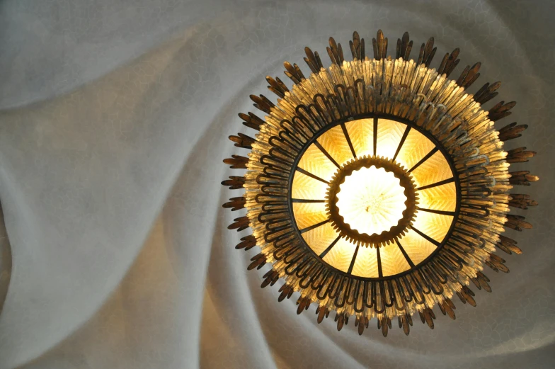 a close up of a light on a ceiling, an art deco sculpture, inspired by Gaudi, pexels contest winner, ornamental halo, golden spirals, frank lloyd wright, cathedral of sun