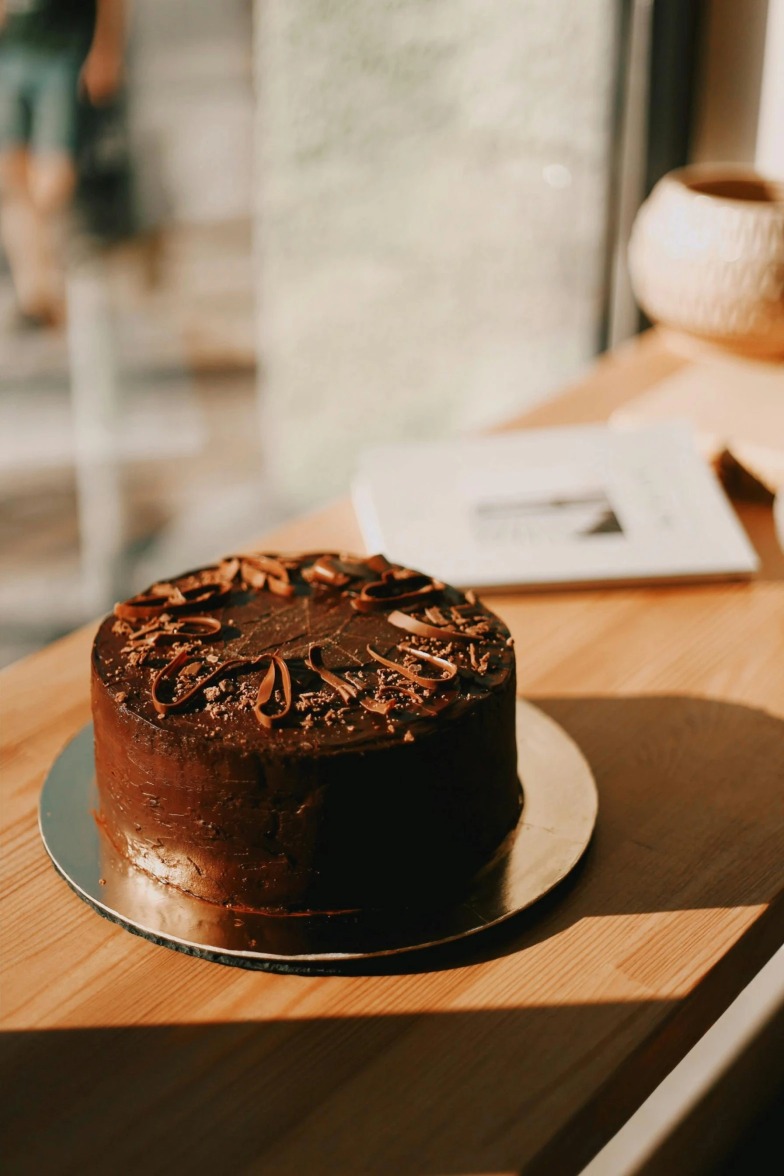 a chocolate cake sitting on top of a wooden table, pexels contest winner, celebration of coffee products, sunlit, all black matte product, full faced