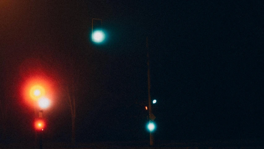 a couple of traffic lights sitting on the side of a road, an album cover, inspired by Elsa Bleda, unsplash, postminimalism, midnight mist streetlights, red and cyan, low quality grainy, spooky photo