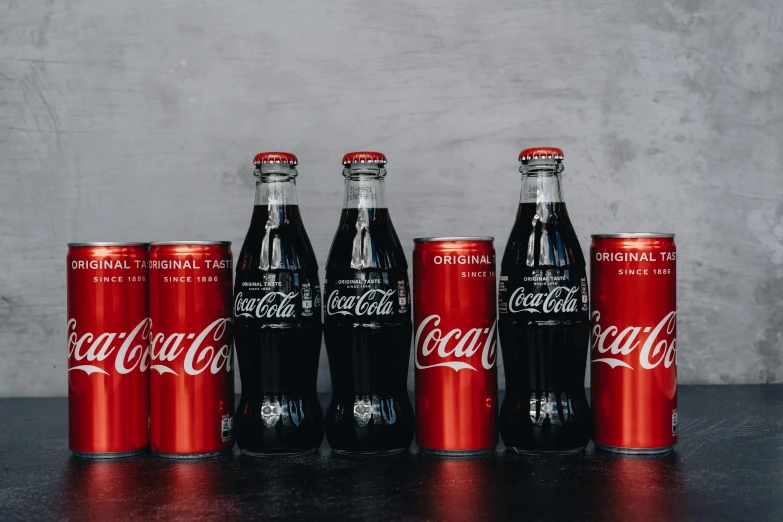 a group of coca colas sitting on top of a table, pexels contest winner, fan favorite, standing with a black background, on a gray background, bottles