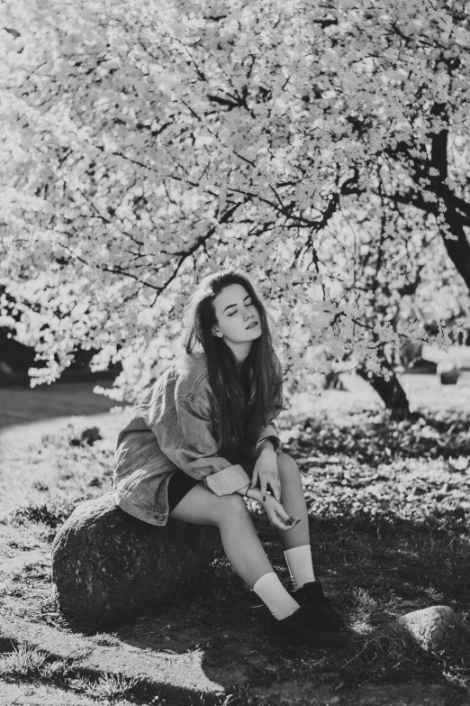 a black and white photo of a woman sitting under a tree, a black and white photo, tumblr, 🌸 🌼 💮, 15081959 21121991 01012000 4k, sadie sink, cherry blossom