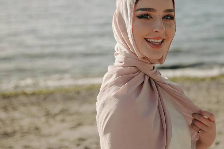 a woman wearing a hijab on the beach, trending on pexels, hurufiyya, light blush, welcoming grin, sarong, stylised