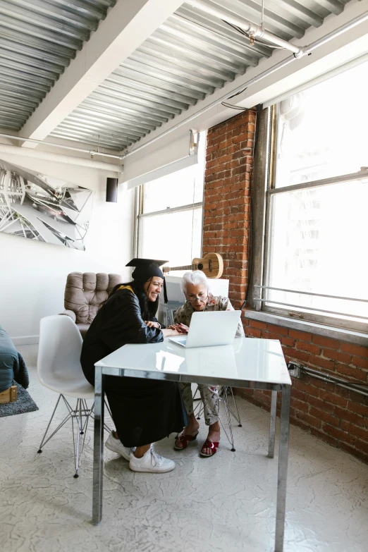 a group of people sitting around a table in a room, trending on unsplash, academic art, wearing an academic gown, working on her laptop, next to window, medium shot of two characters