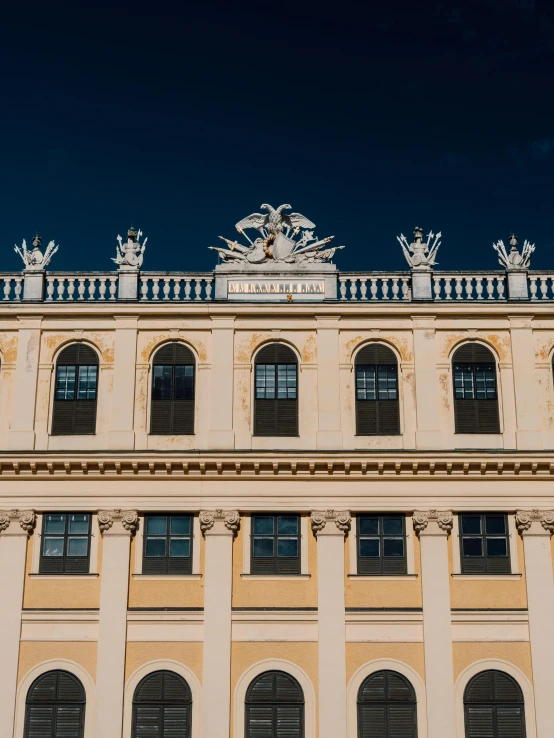 a large building with a clock on top of it, a photo, by Sebastian Spreng, pexels contest winner, neoclassicism, yellow windows and details, vienna city, profile image, symmetrical crown