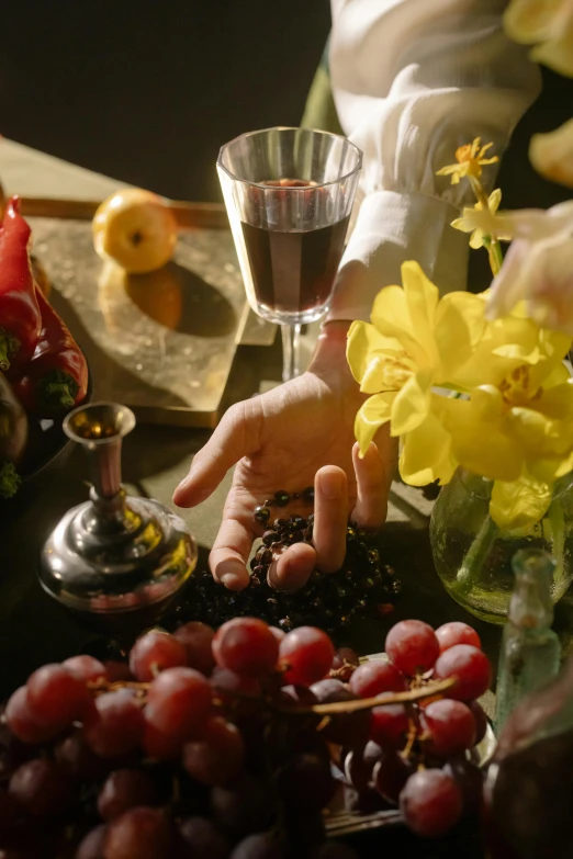 a close up of a person holding a glass of wine, a still life, inspired by Caravaggio, renaissance, edible flowers, film still promotional image, place setting, religious