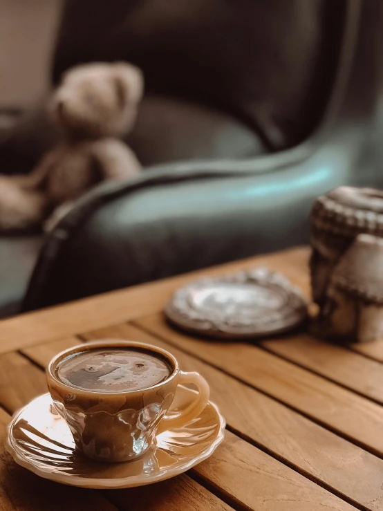 a cup of coffee sitting on top of a wooden table, by irakli nadar, hurufiyya, plush furnishings, thumbnail, serena malyon, chocolate