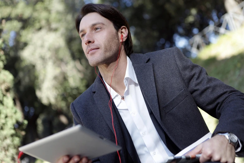 a man sitting on a bench with a laptop and headphones, inspired by Nelson Alexander Ross, wearing a blazer, using a magical tablet, **cinematic, : :