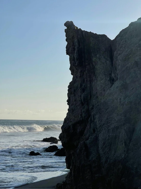 a large rock sitting on top of a beach next to the ocean, profile image, oceanside, ((monolith)), big waves