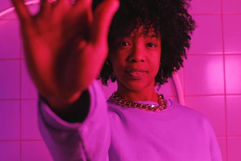 a woman making a stop sign with her hand, pexels contest winner, afrofuturism, brightly lit purple room, looking straight to camera, 2 1 savage, youthful taliyah