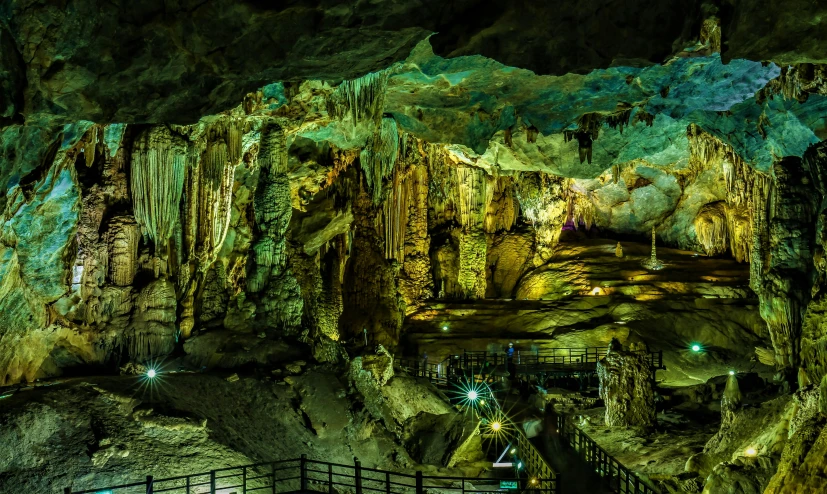 a group of people standing inside of a cave, neon blue and yellow lights, karst pillars forest, thumbnail, panoramic