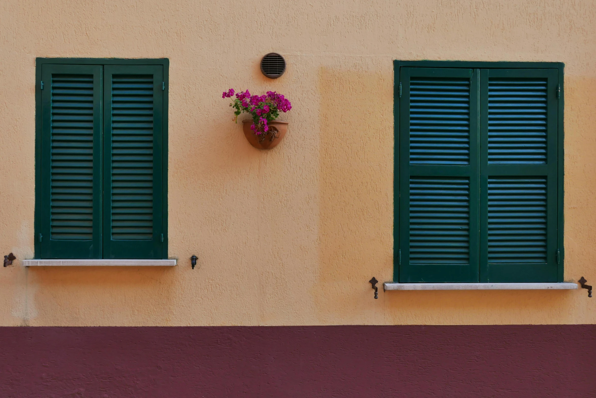 a red fire hydrant sitting on the side of a building, a minimalist painting, inspired by Clarice Beckett, pexels contest winner, cyan shutters on windows, yellow and green scheme, mediterranean vista, green and purple