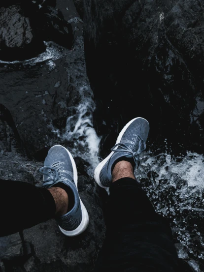 a person standing on a rock next to a river, pexels contest winner, running shoes, in gunmetal grey, white water, indoor shot