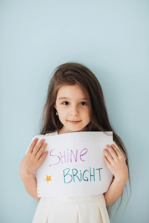 a little girl holding a sign that says shine bright, shutterstock contest winner, fluorescent, shiny materials, profile image, pokimane