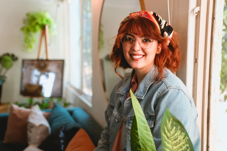 a woman standing in a living room holding a plant, pexels contest winner, red haired young woman, teal headband, with square glasses, charli bowater and artgeem