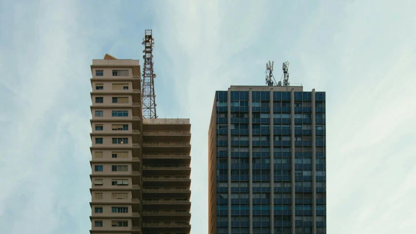 a couple of tall buildings next to each other, a photo, pexels contest winner, brutalism, radio signals, repairing the other one, 2000s photo, commercially ready