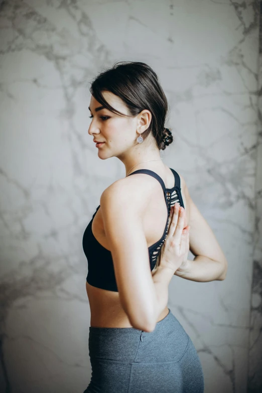 a woman in a sports bra top doing yoga, by Carey Morris, trending on pexels, renaissance, looking from shoulder, editorial image, standing, backbone