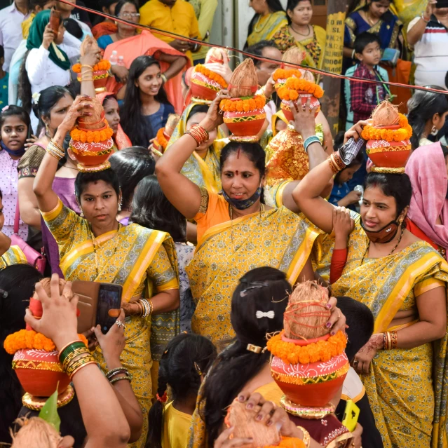 a group of women standing in front of a crowd of people, samikshavad, orange and yellow costume, avatar image, square, holy ceremony