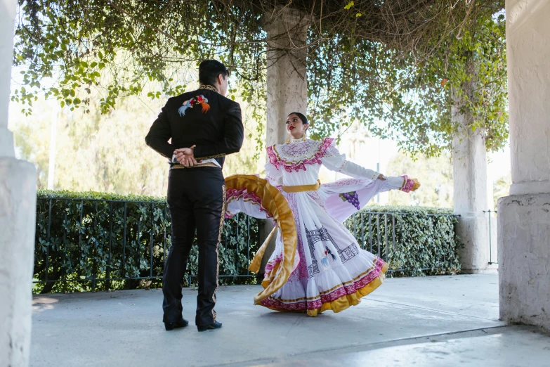 a couple of people standing next to each other, by Lisa Milroy, pexels contest winner, arabesque, she is mexican, full dress uniform, patio, choreographed