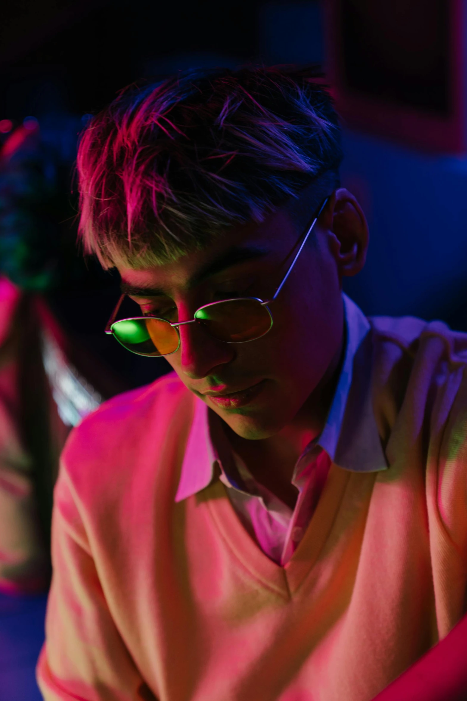 a man sitting in front of a laptop computer, an album cover, by Cosmo Alexander, trending on pexels, neon sunglasses!, reflecting light in a nightclub, androgynous person, male teenager