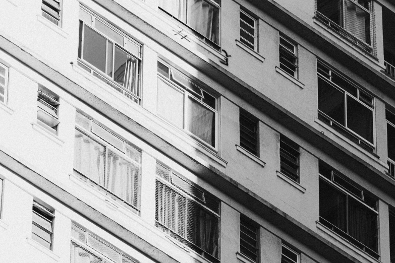a black and white photo of a tall building, inspired by André Kertész, unsplash contest winner, window with rio de janeiro view, shadow gradient, old apartment, house windows