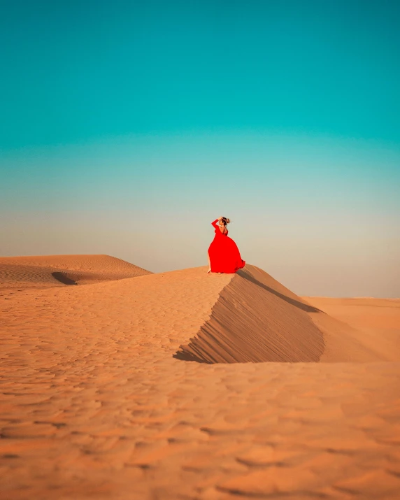 a woman in a red dress sitting on top of a sand dune, pexels contest winner, saturated colors, the red queen, an arab standing watching over, gif