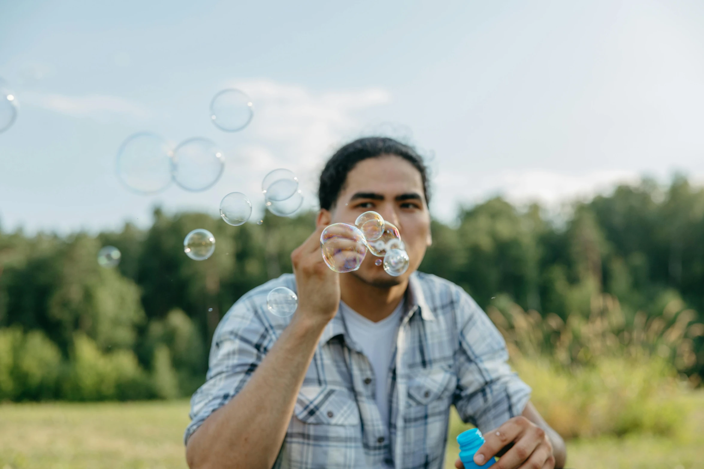 a man is blowing bubbles in a field, pexels contest winner, indigenous man, picnic, avatar image, foamy bubbles