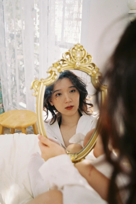 a woman is looking at her reflection in a mirror, a picture, inspired by Kim Jeong-hui, pexels contest winner, rococo, soft oval face, 35mm color photo, half asian, gold