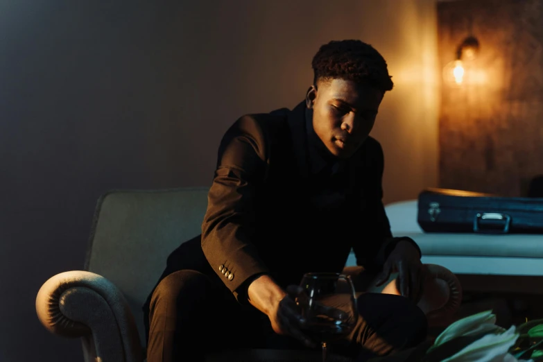 a woman sitting on a couch holding a glass of wine, by Adam Marczyński, pexels contest winner, visual art, black teenage boy, wearing a worn out suit, middle of the night, comforting